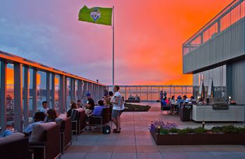 people sitting at tables on a roof terrace at sunset